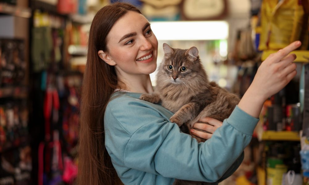 Happy woman with her cute cat in pet shop