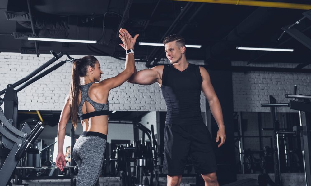 sportive couple giving high five to each other in gym