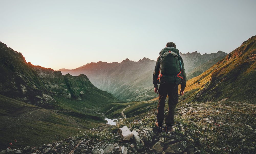 Man hiking at sunset mountains with heavy backpack Travel Lifestyle wanderlust adventure concept summer vacations outdoor alone into the wild