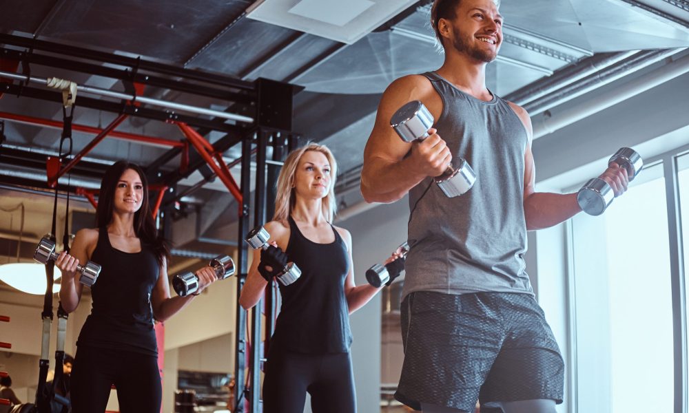 Group of people exercising with dumbbells in the fitness club or gym.
