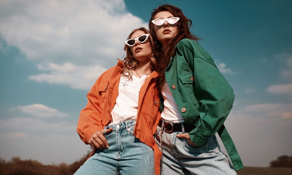 High fashion portrait of two stylish beautiful woman in trendy jackets and jeans posing outdoor. Vogue style.
