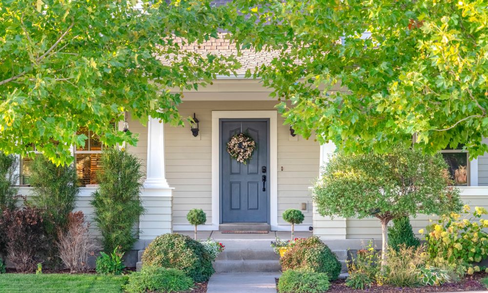 Front door of a home surrounded by leafy trees. Front door and porch of a home surrounded by leafy green trees in a city suburb in a street view