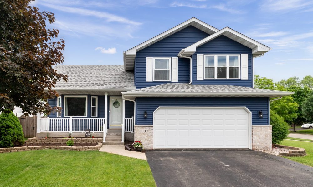 Exterior of a suburban home with blue siding, a white front porch, and white shutters.