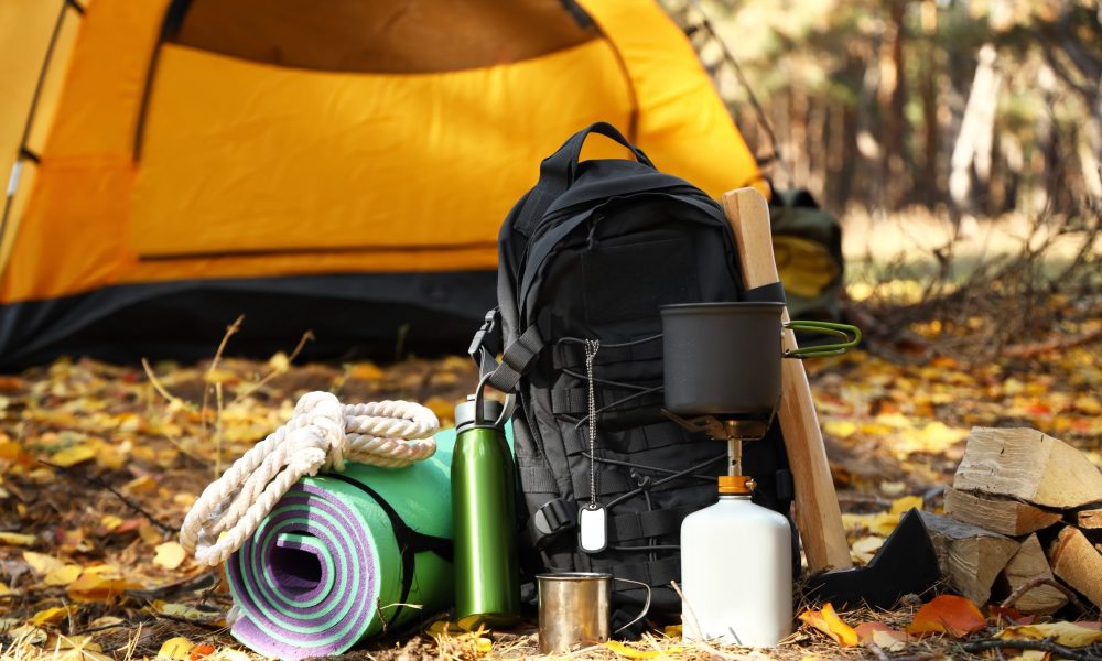 Tourist's survival kit and camping tent in autumn forest