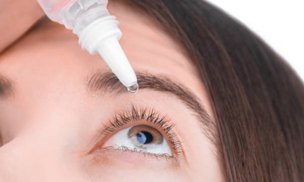Closeup female hand is holding little bottle with healing drops. Young woman is going to drip medication, artificial tear into eye. Treatment and prevention ophthalmic diseases concept.