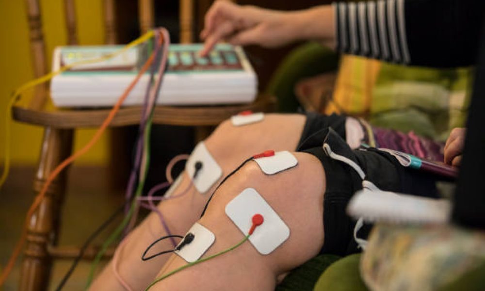 Mid Adult Woman Using Electrostimulator at Home.