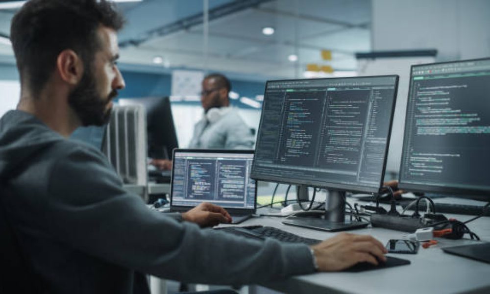 Diverse Office: Enthusiastic White IT Programmer Working on Desktop Computer. Male Specialist Creating Innovative Software. Engineer Developing App, Program, Video Game. Writing Code in Terminal