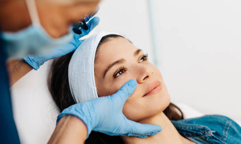 Attractive young woman is getting a rejuvenating facial injections at beauty clinic. The expert beautician is filling female wrinkles by botulinum.