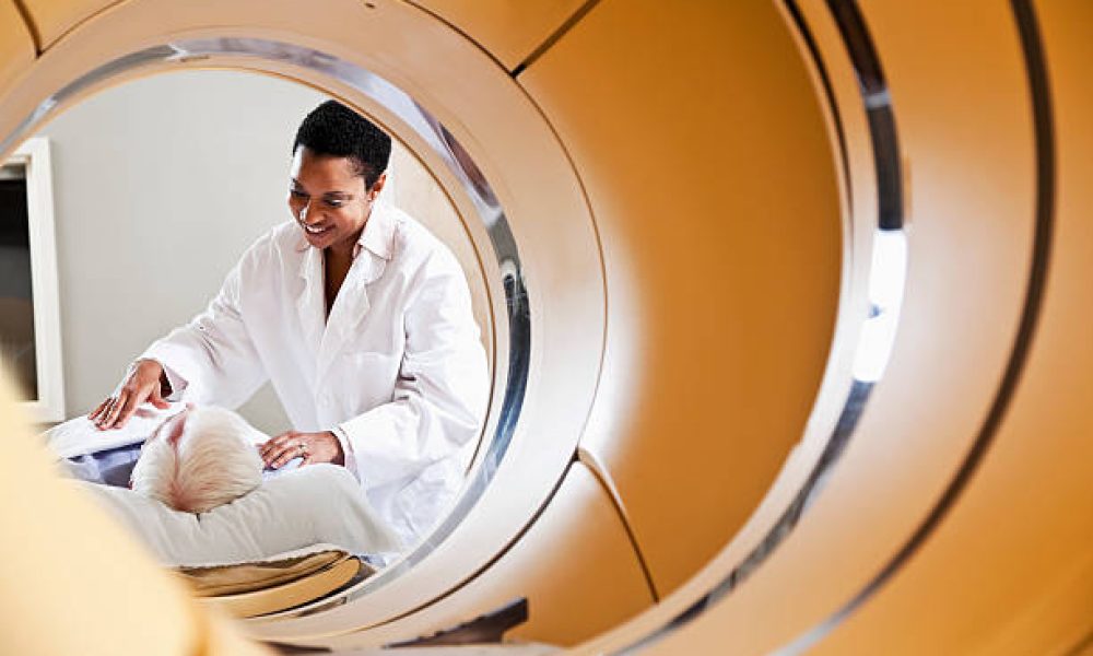 View of radiologist or technician with senior male patient through an integrated PET-CT scanner.