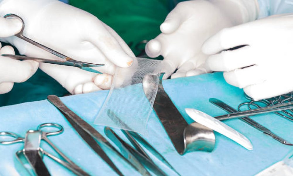 surgeon chops mesh for hernia