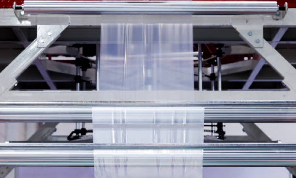 plastic packaging film on the automatic packing machine in food product factory. industrial and technology concept.