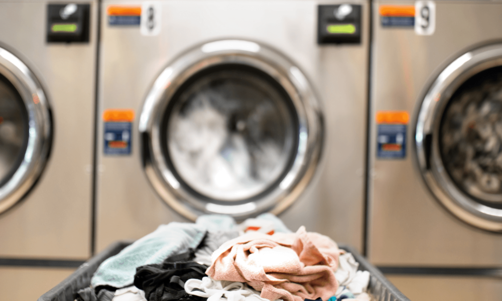 A basket full of clothes sitting in front of a row of washing machines