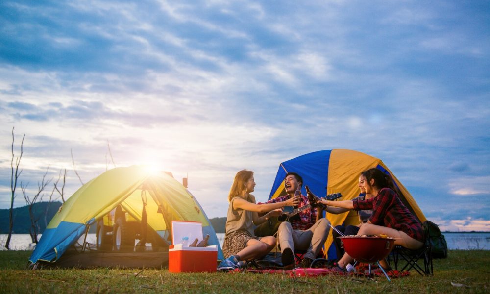 group-man-woman-enjoy-camping-picnic-barbecue-lake-with-tents-background-young-mixed-race-asian-woman-man-young-people-s-hands-toasting-cheering-bottles-beer_1253-1041